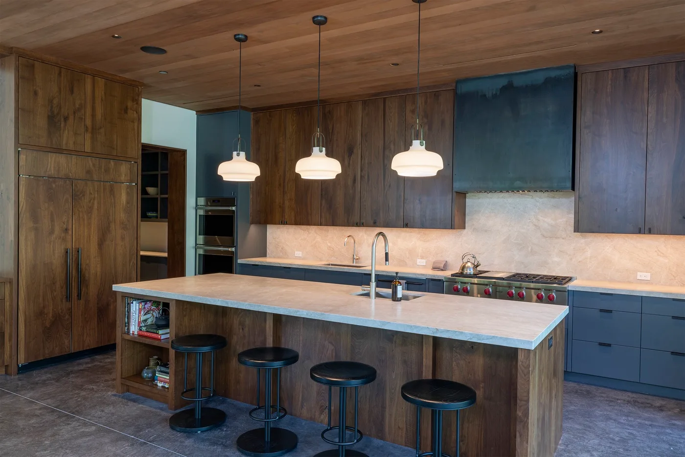 Una cocina moderna cuenta con una amplia isla bajo tres lámparas colgantes.