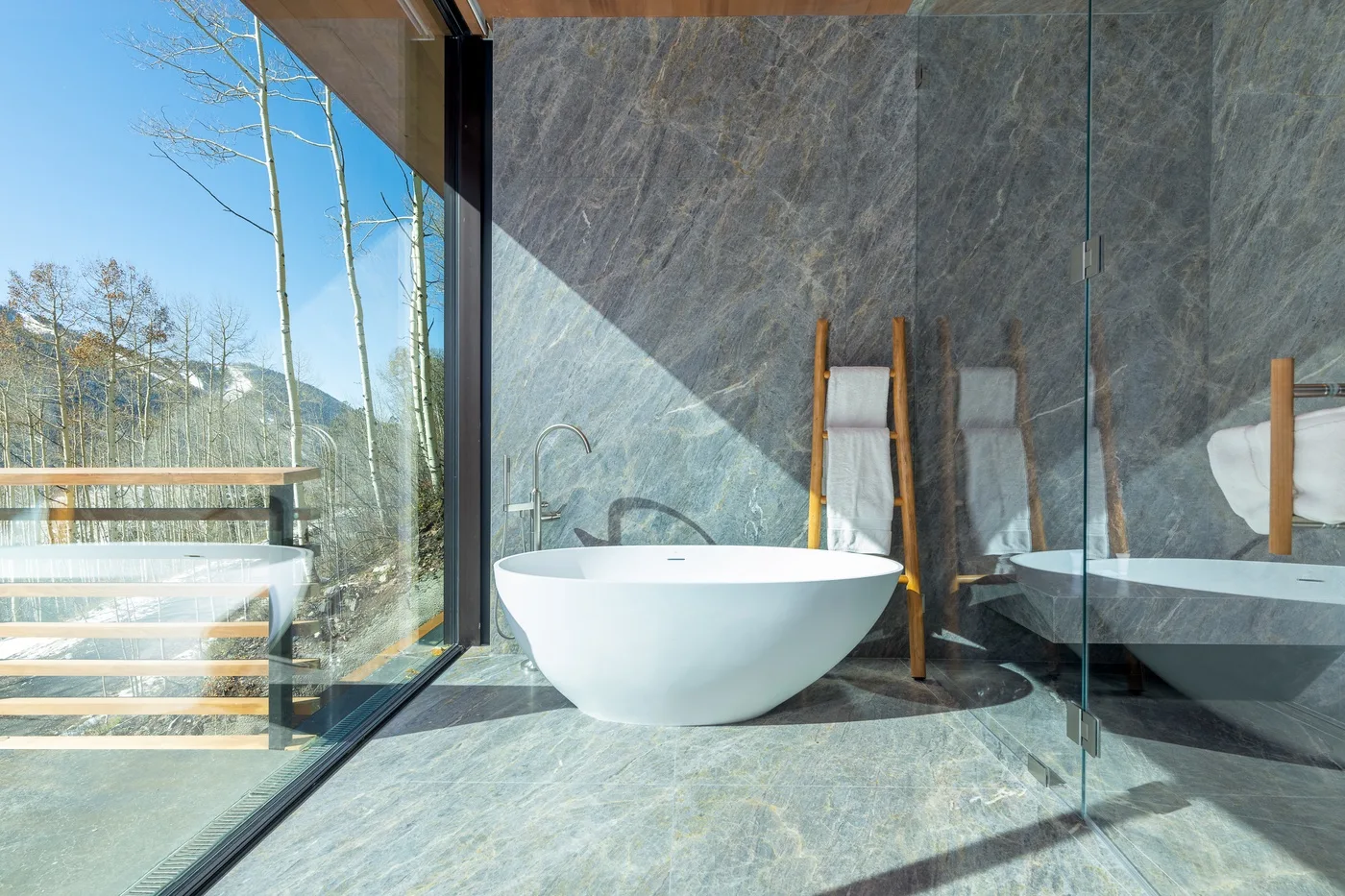 Un baño moderno con una bañera exenta junto a una gran ventana.