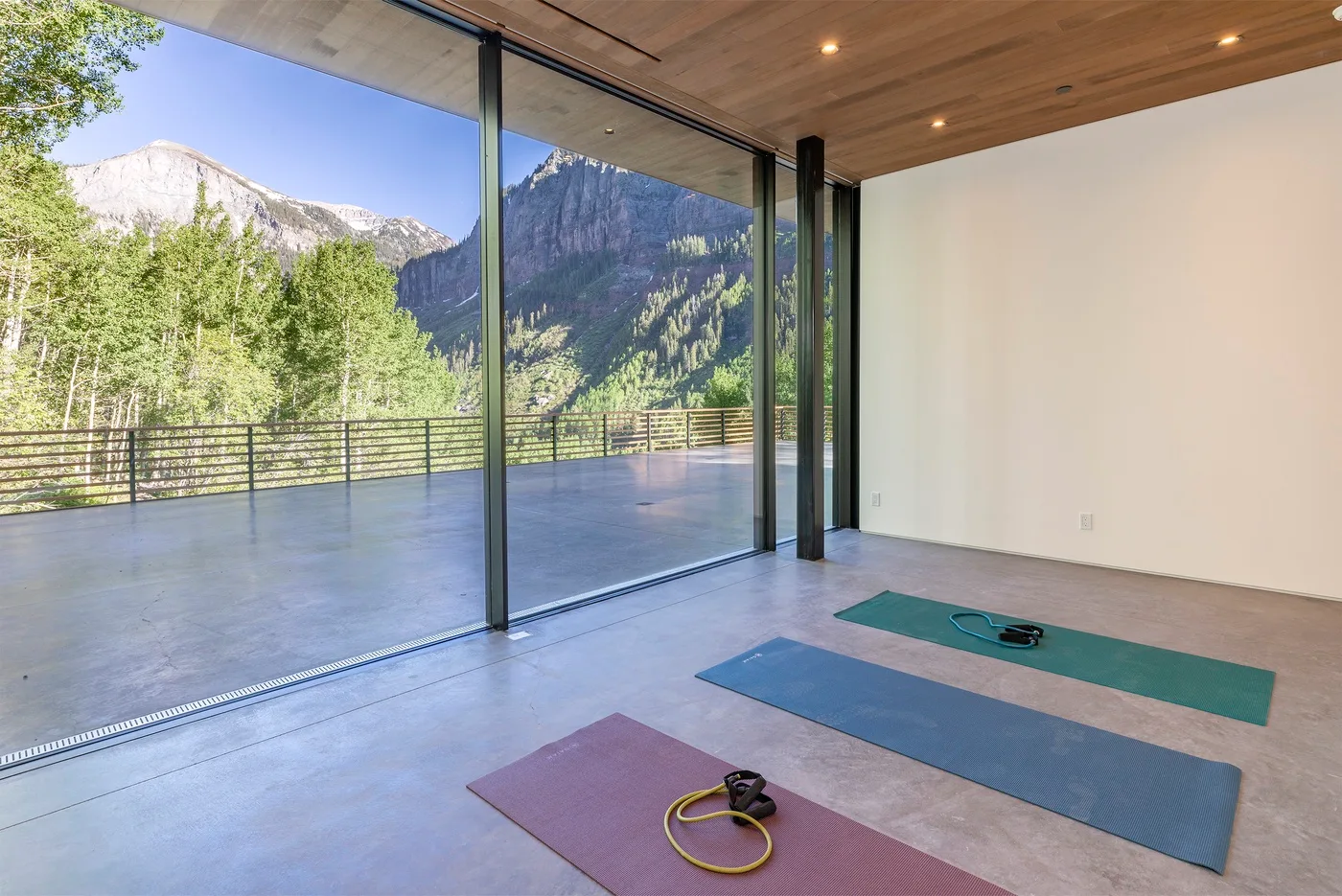 Una luminosa zona de yoga se abre a una terraza con vistas a las montañas.