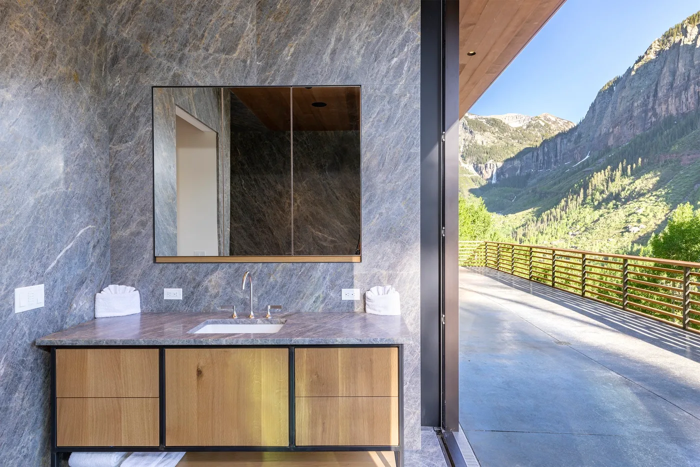 Un tocador de baño con espejo se abre a una vista de montaña.