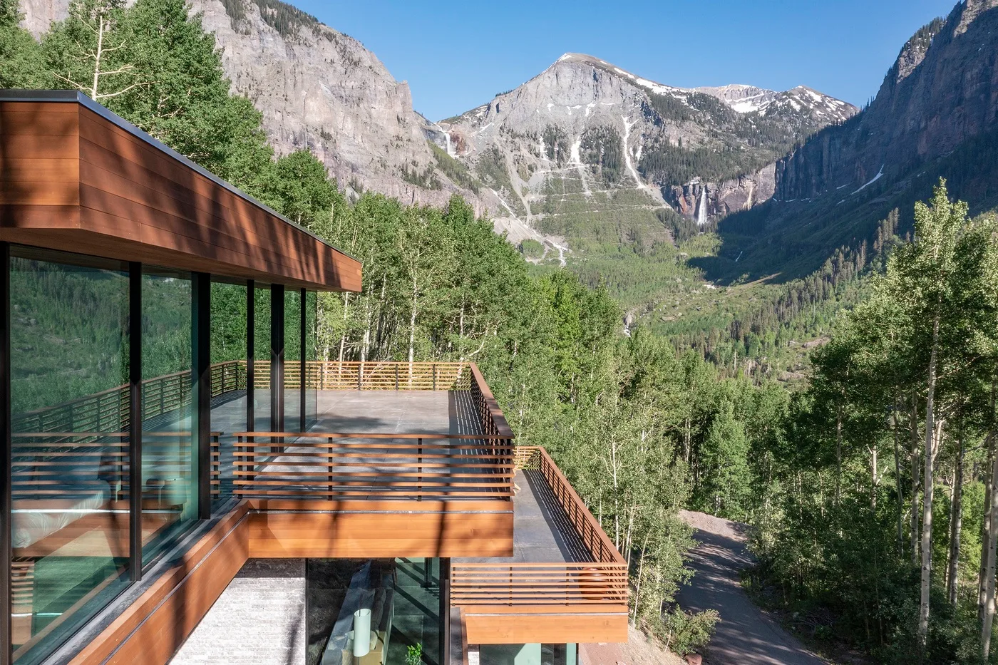 Un edificio moderno con terrazas de madera da a un valle montañoso boscoso.
