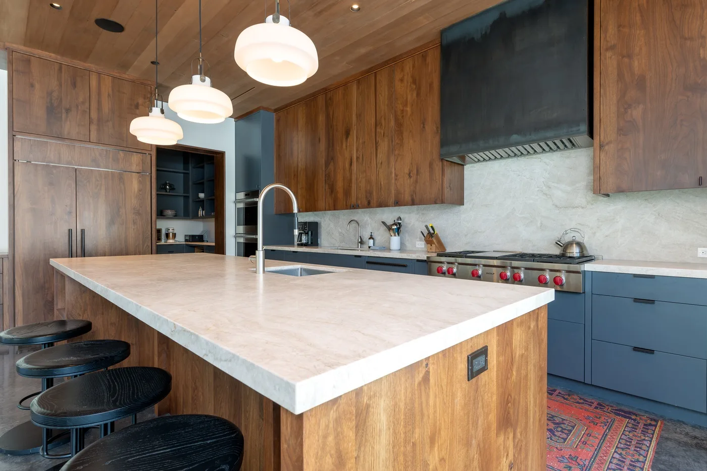Una cocina moderna con una gran isla, luces colgantes y gabinetes de madera.