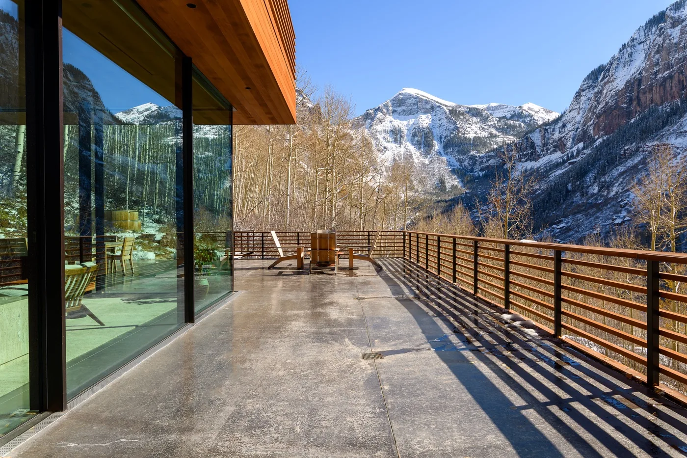 Una amplia terraza exterior con puertas de vidrio ofrece vistas a un valle montañoso.