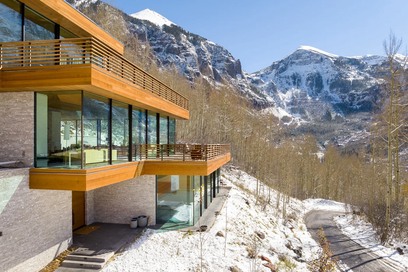 Un edificio moderno con fachada de vidrio se encuentra junto a un paisaje montañoso nevado.