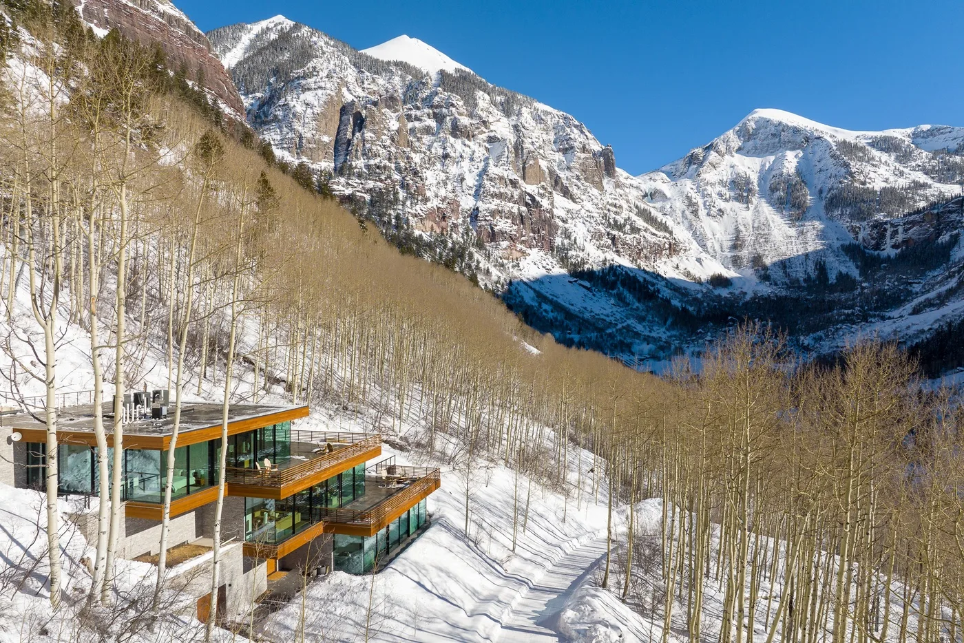 Un edificio moderno se encuentra entre árboles nevados bajo una cordillera.
