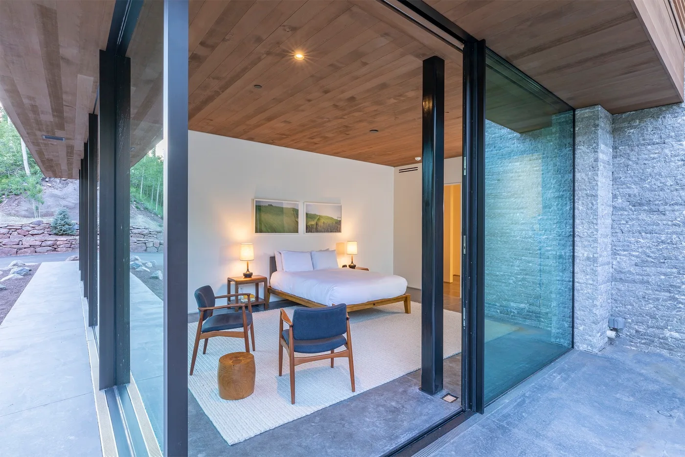 Un dormitorio con cama, mesas de noche y sillas bajo un techo de madera.