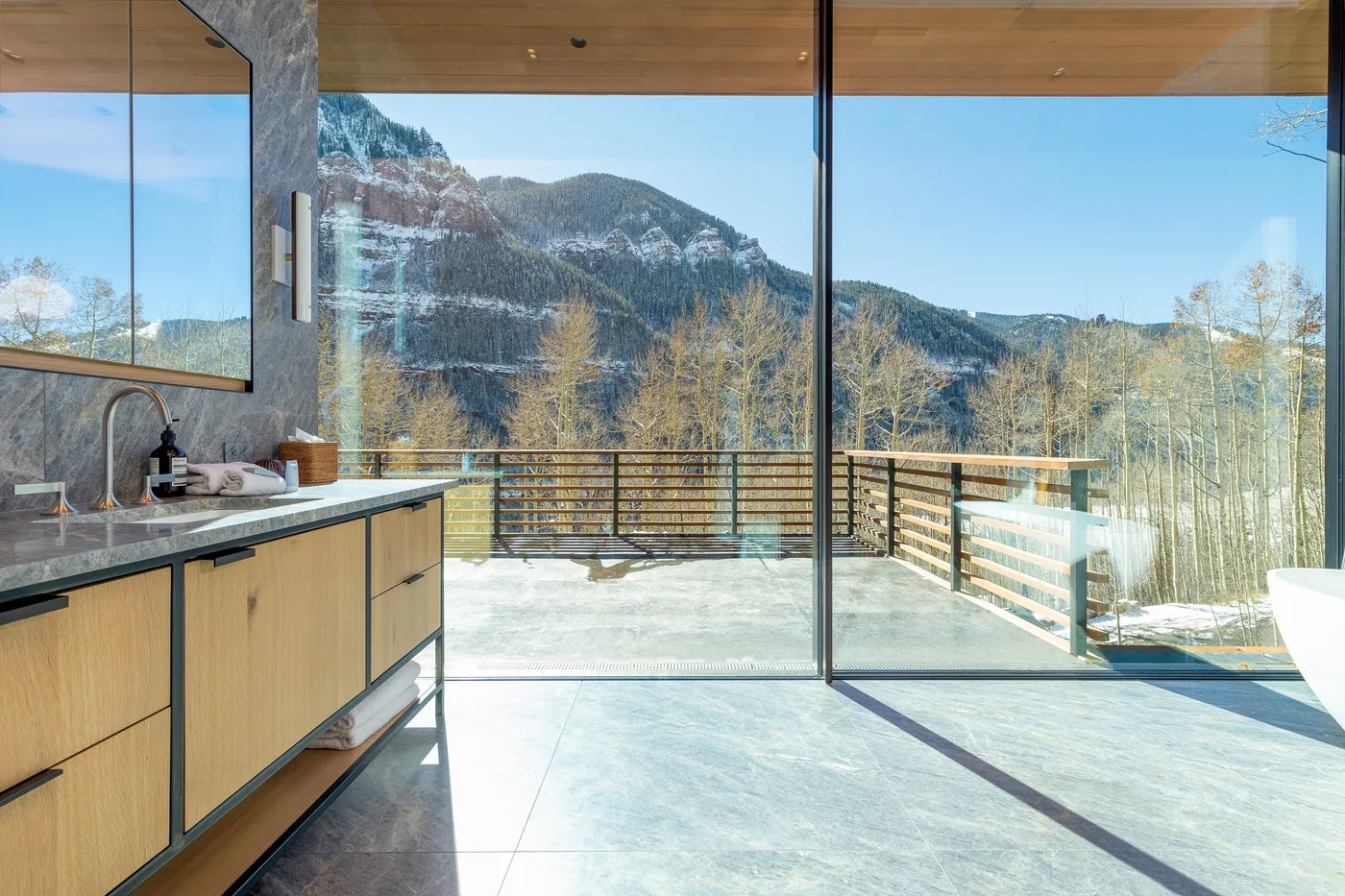 Una cocina luminosa se abre a través de puertas de vidrio a una terraza con vistas a las montañas.