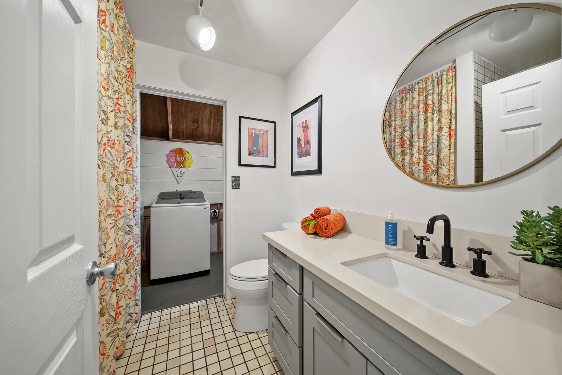 Un baño con un tocador largo, lavabo y una zona de ducha con cortina.