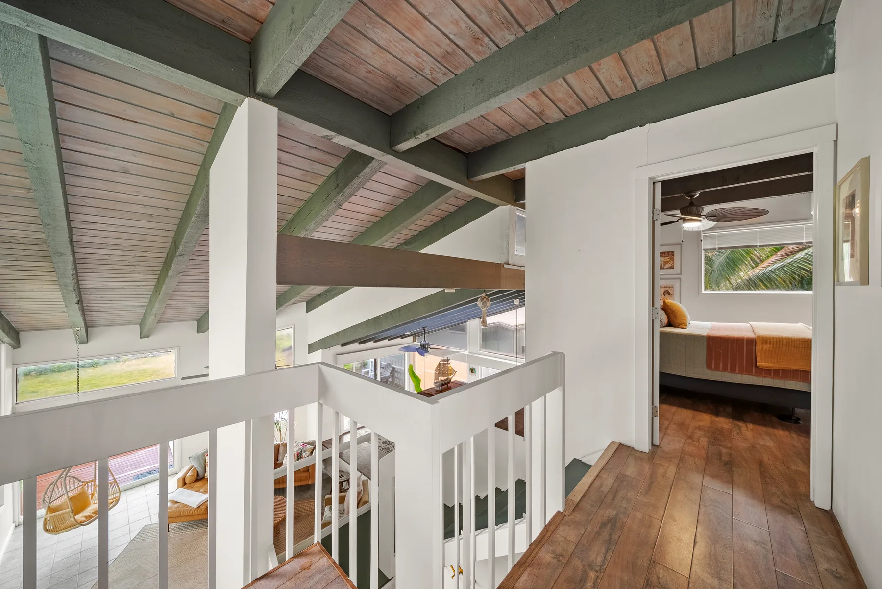 Un descansillo interior tipo loft con vigas expuestas y vista a un dormitorio.