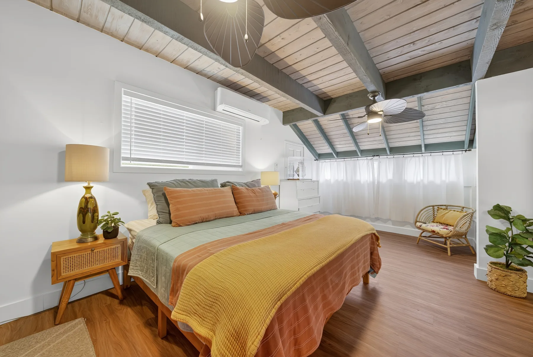 Un dormitorio con una cama, una mesita de noche y vigas de madera a la vista.