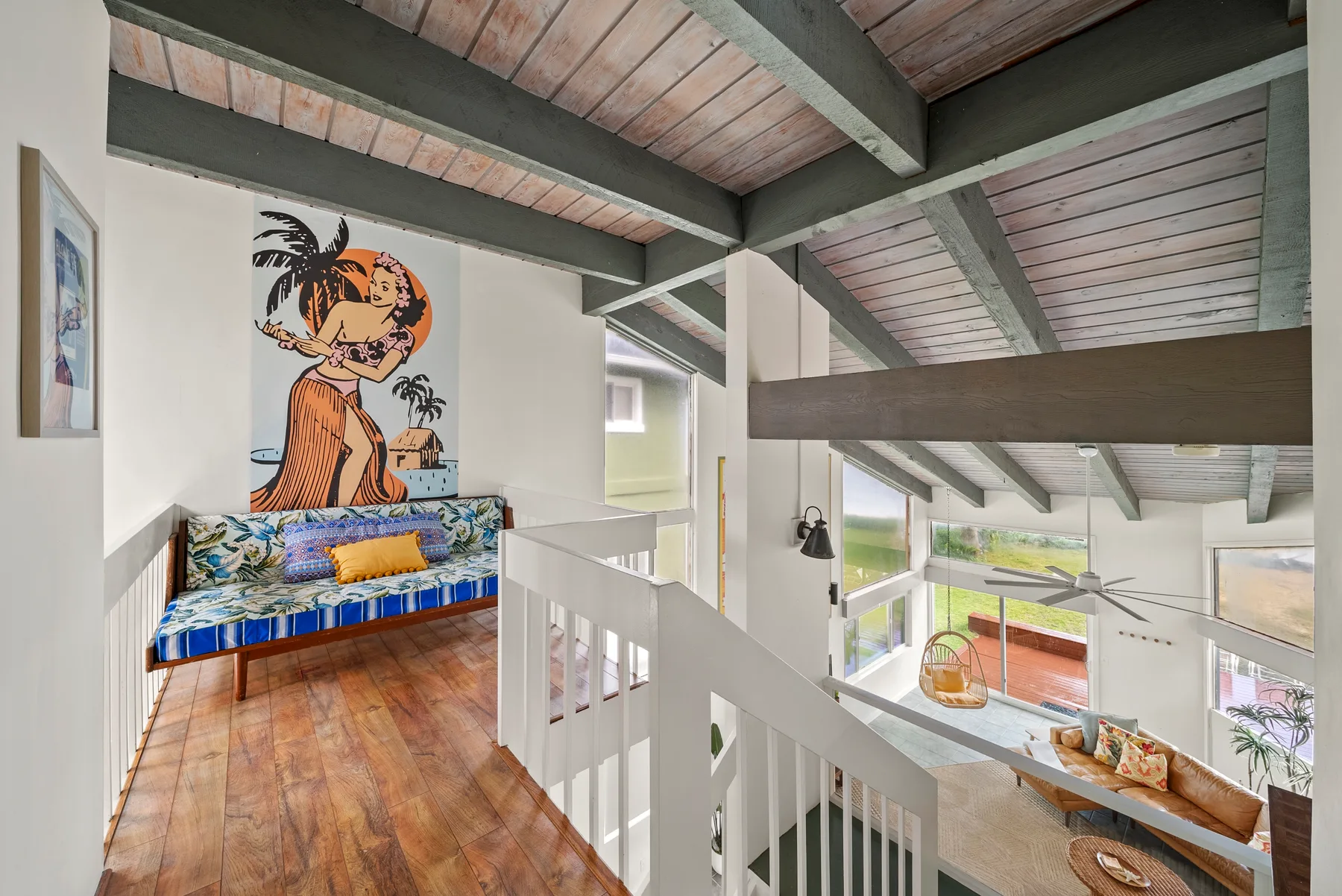 Una luminosa sala tipo loft con una escalera blanca y arte colorido en la pared.
