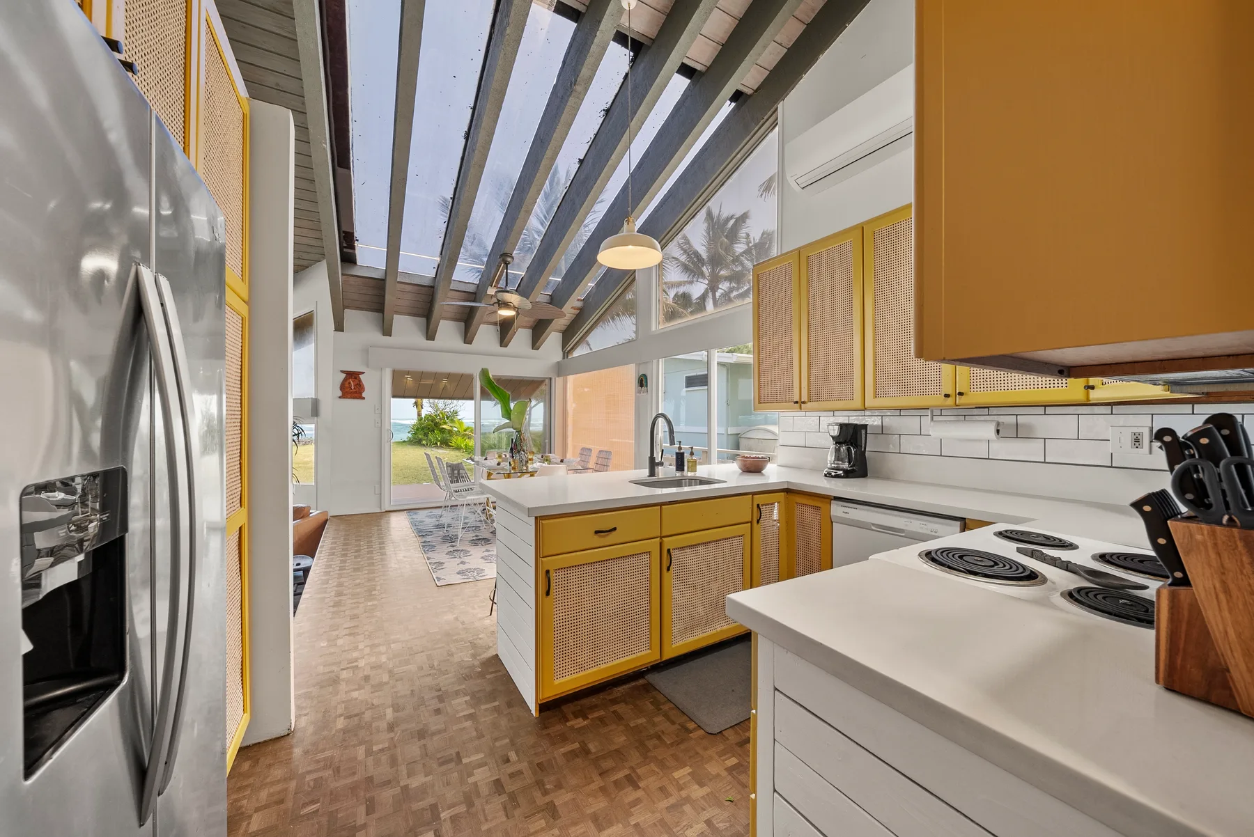 Una cocina luminosa con una isla central, un refrigerador de acero inoxidable y ventanas grandes.