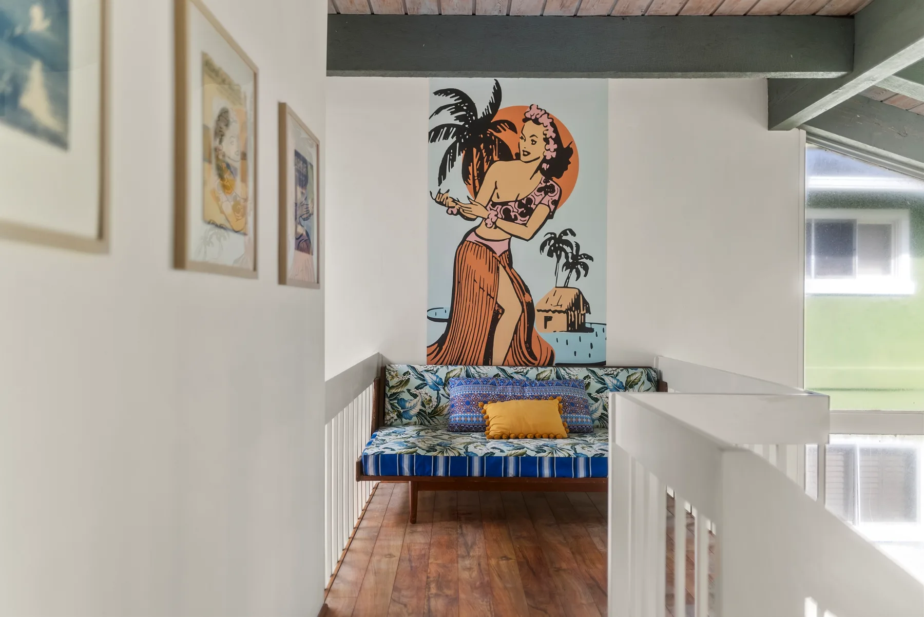 Una pequeña zona de estar interior con un banco acolchado bajo un mural colorido.