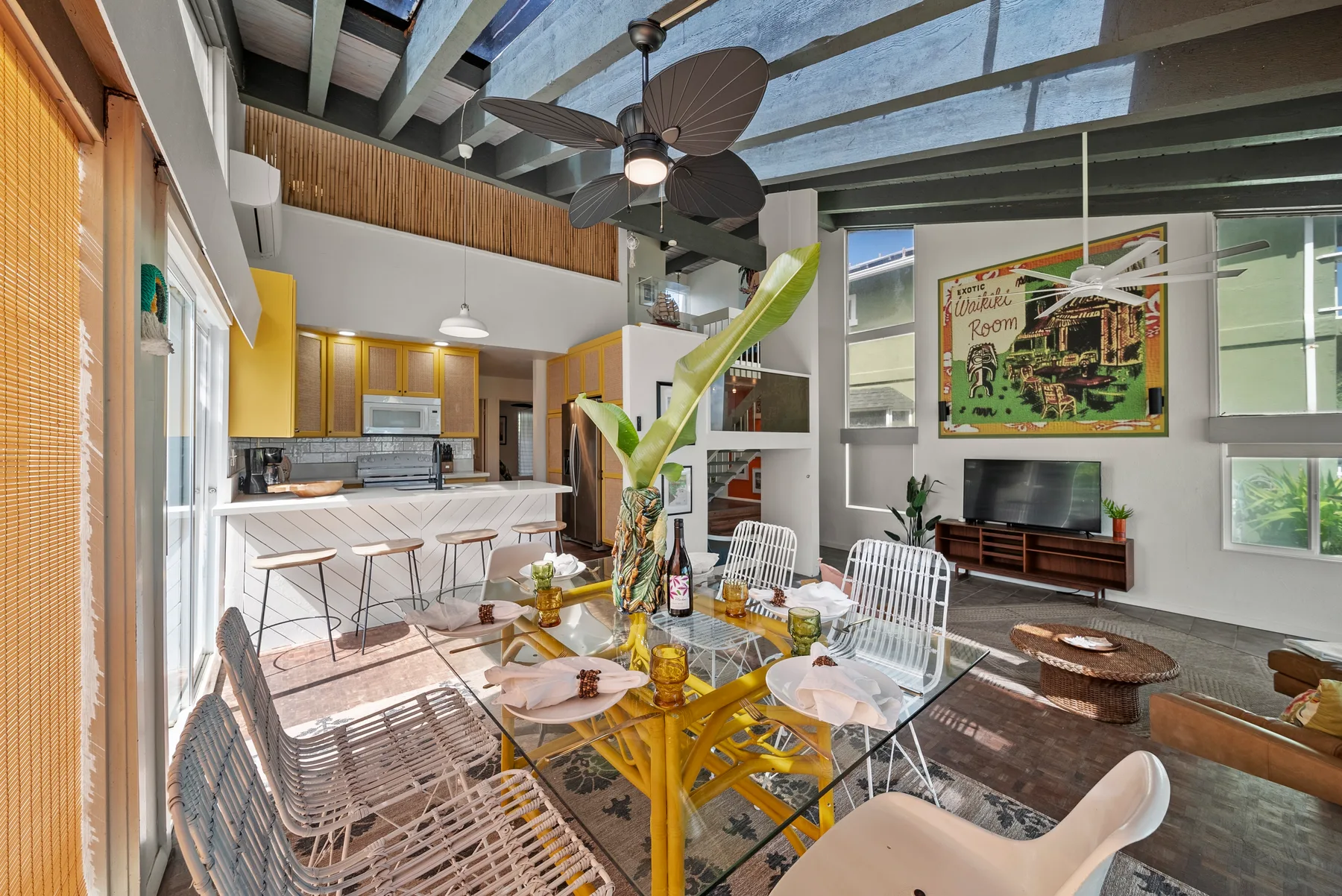 Sala y cocina de concepto abierto con una mesa de comedor bajo un ventilador de techo.