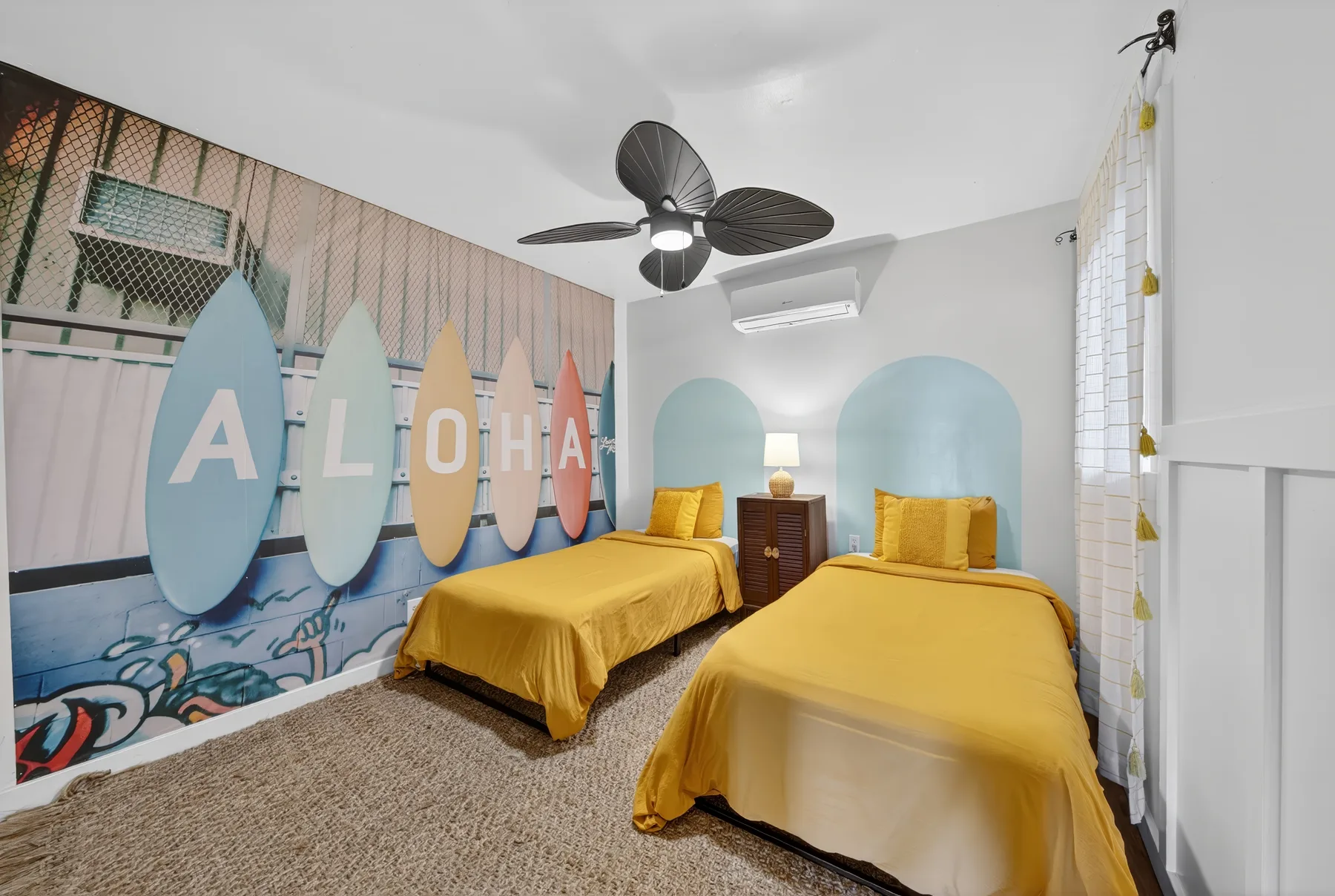 Un dormitorio con dos camas y decoraciones de pared coloridas con forma de tabla de surf.