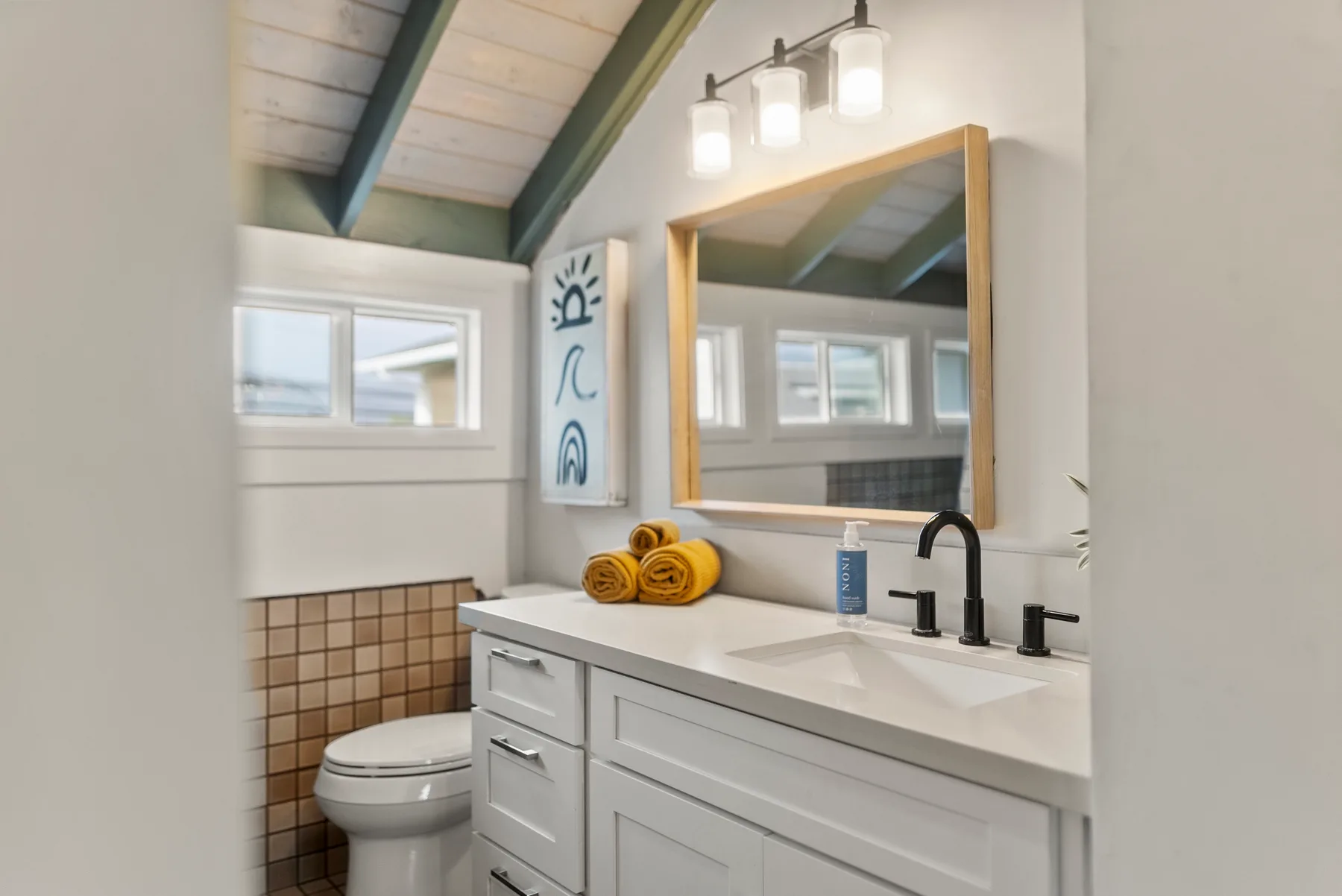 Un tocador de baño con espejo y lavabo está junto a un inodoro.