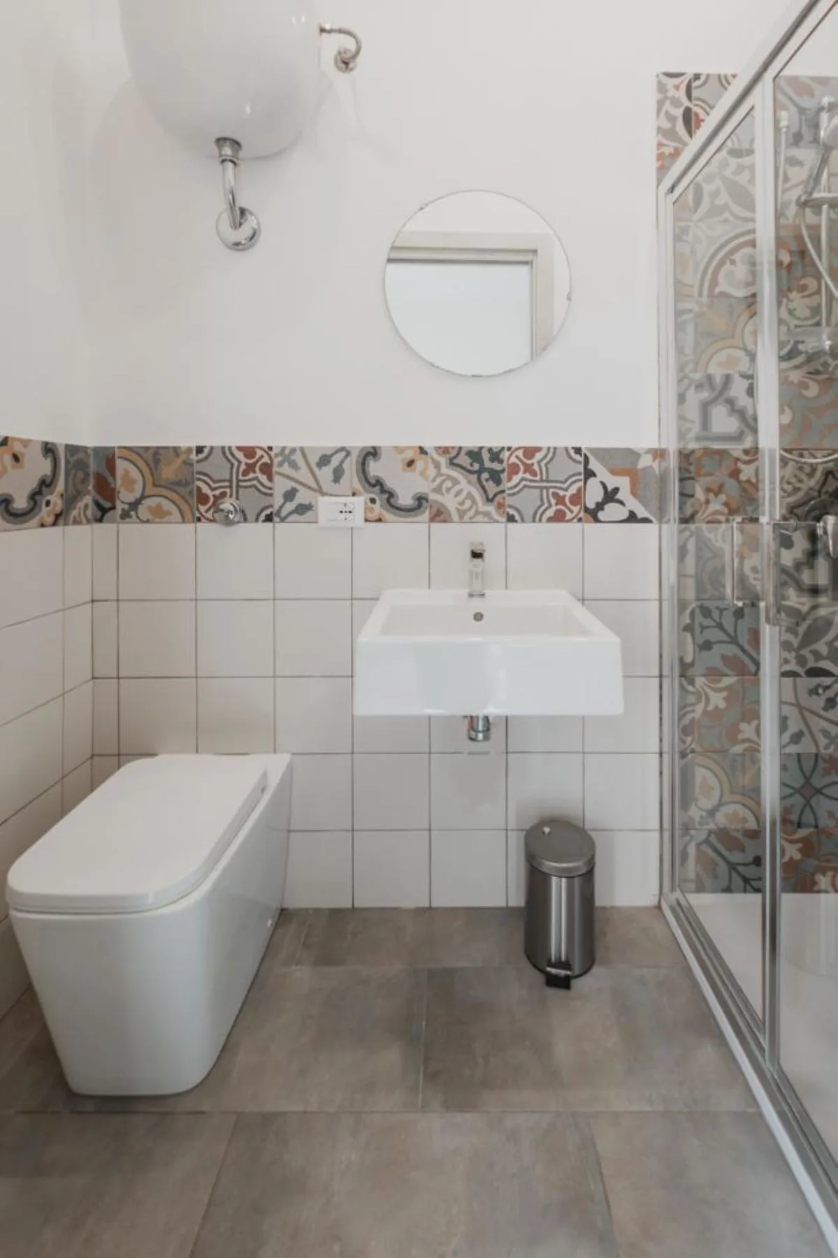 A bathroom with a wall-mounted sink, toilet, and glass shower.