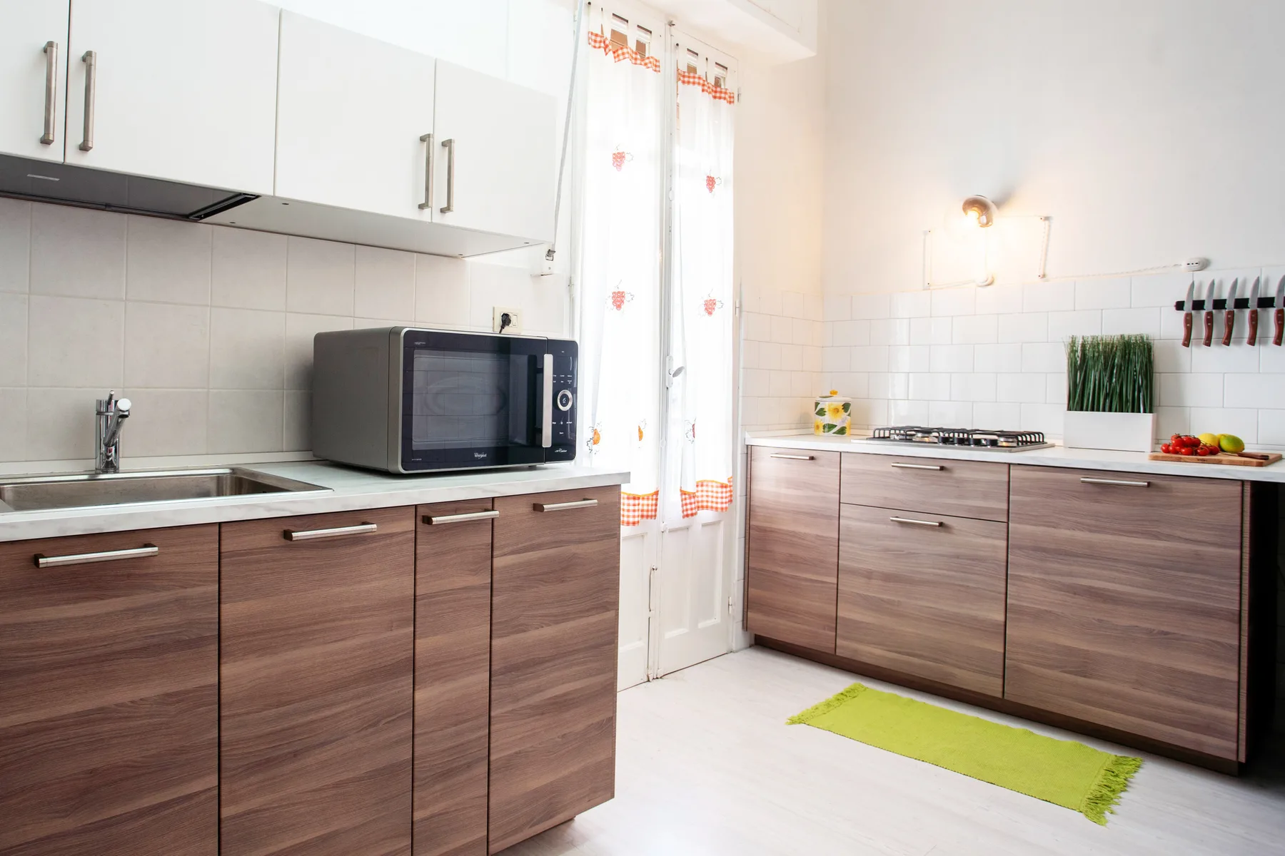A bright kitchen with wood-toned cabinets and a countertop microwave.