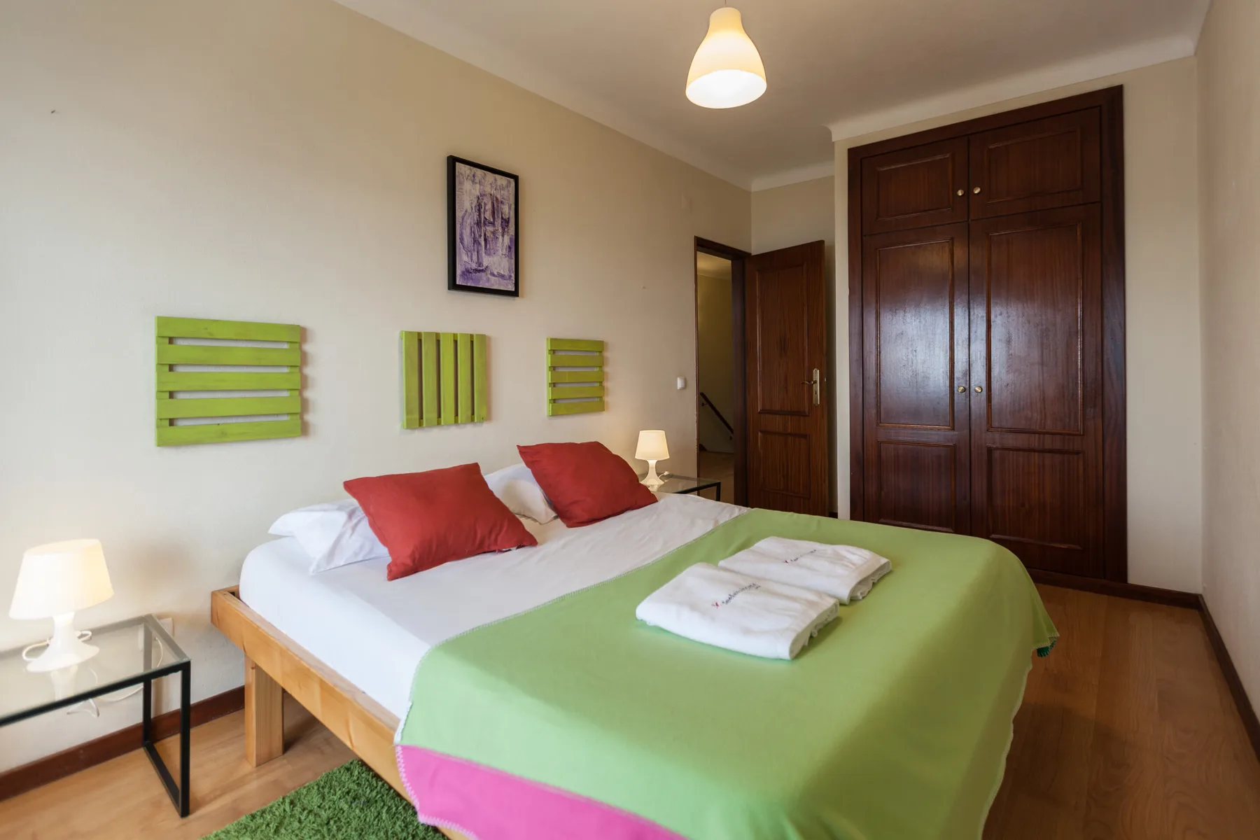 Un dormitorio con una cama vestida con ropa de cama verde y blanca.