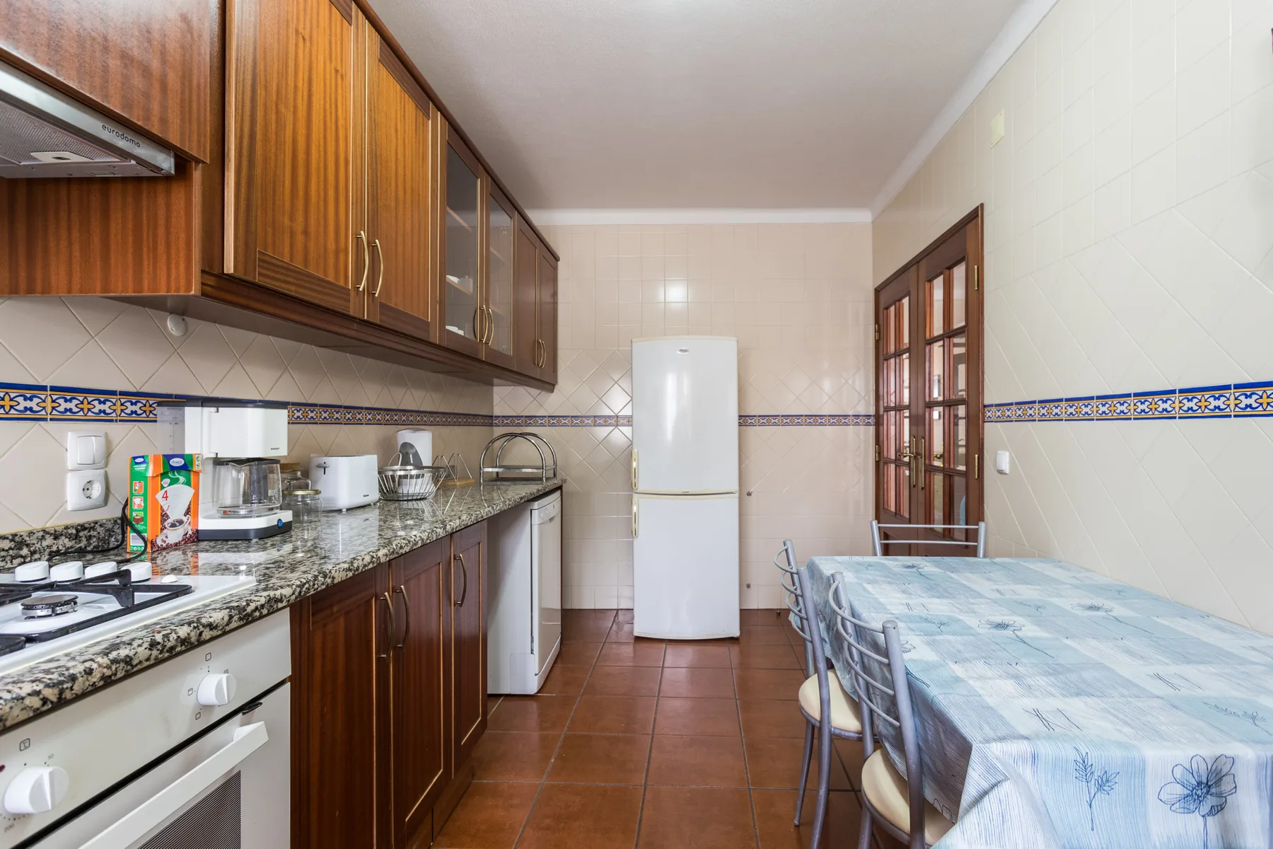 A kitchen with wooden cabinets, a refrigerator, and a dining table.