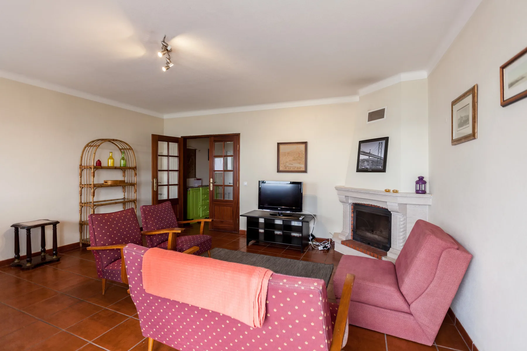 A living room with pink seating, a television, and a fireplace.