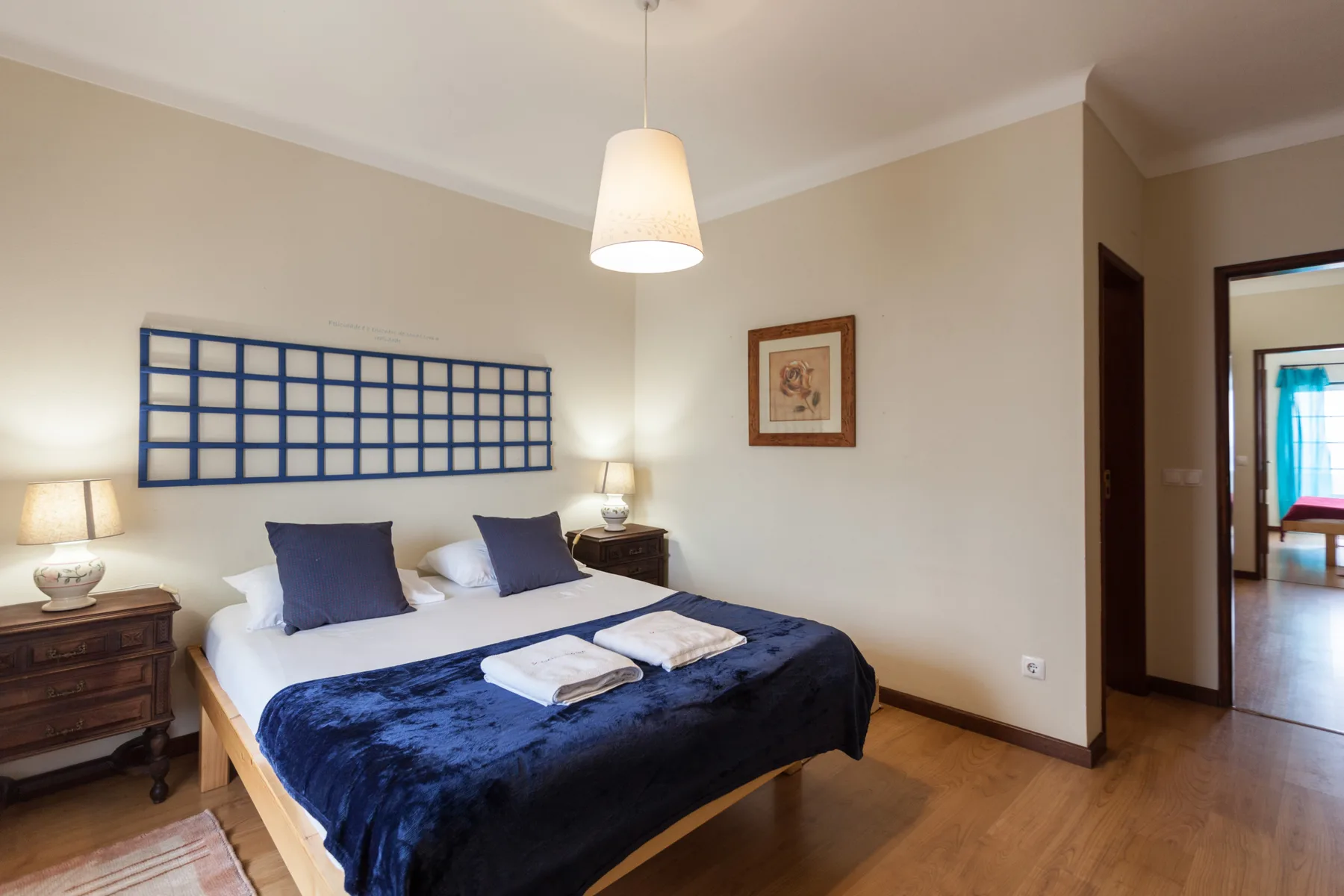 A bedroom with a double bed, dark blue bedding, and bedside tables.