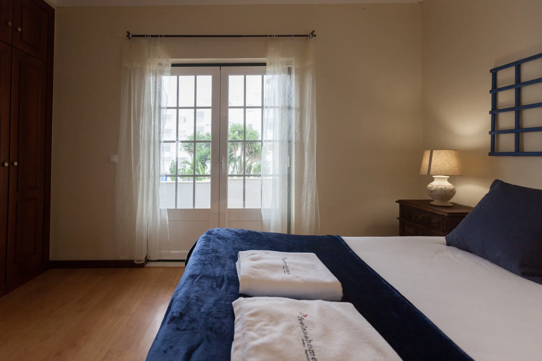 Bedroom with a bed and glass doors opening onto a leafy outdoor area.