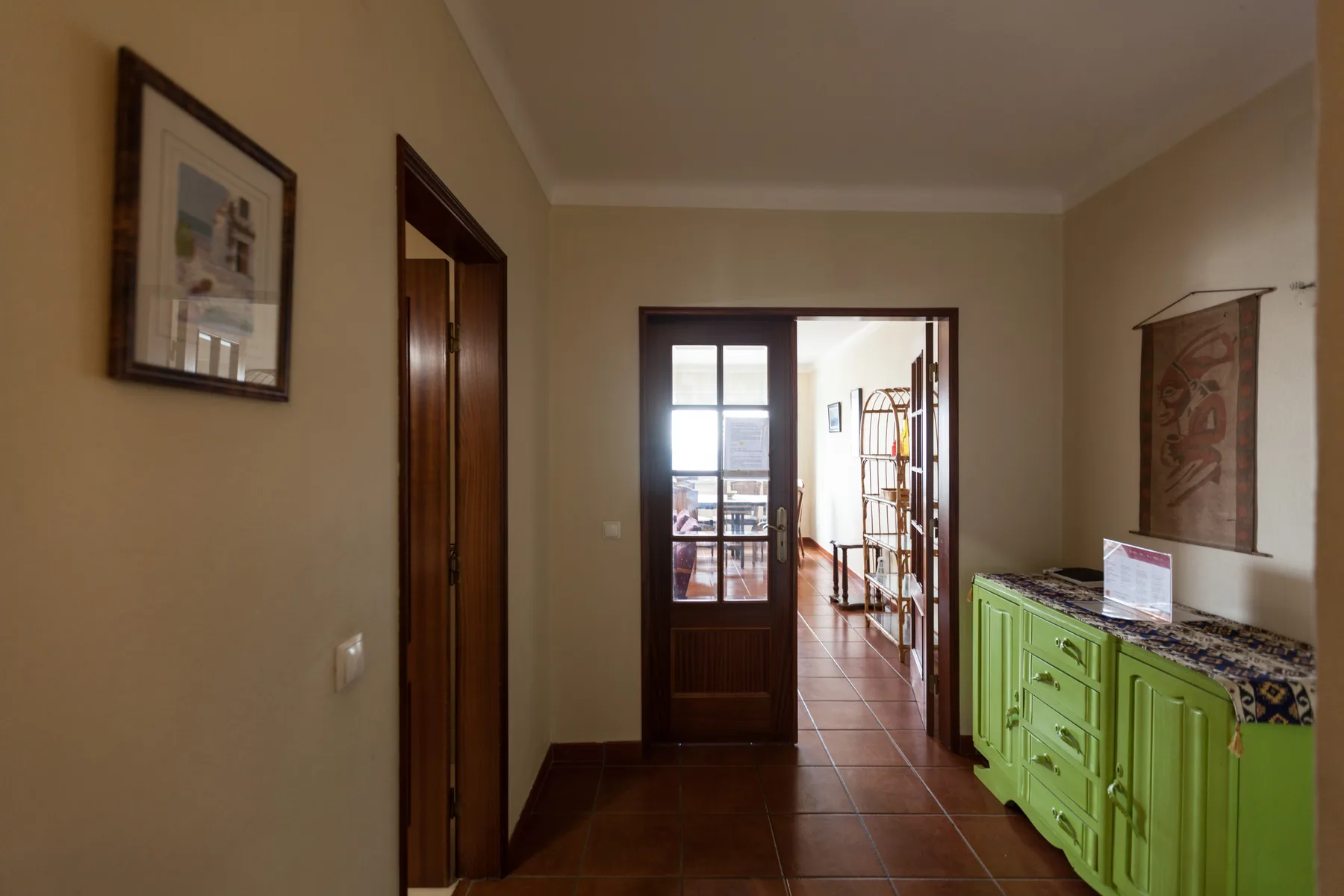 A hallway with a dark wooden doorway and a green cabinet along the wall.