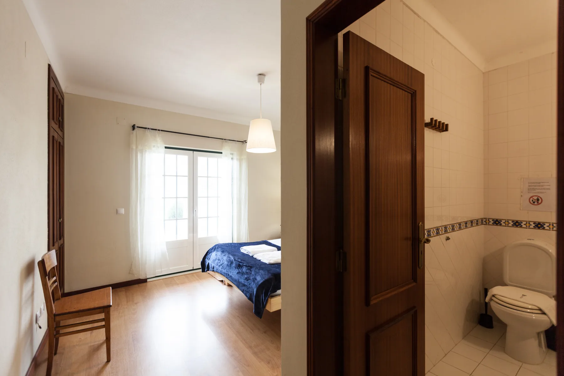 Un dormitorio con una cama junto a una ventana y un baño contiguo.