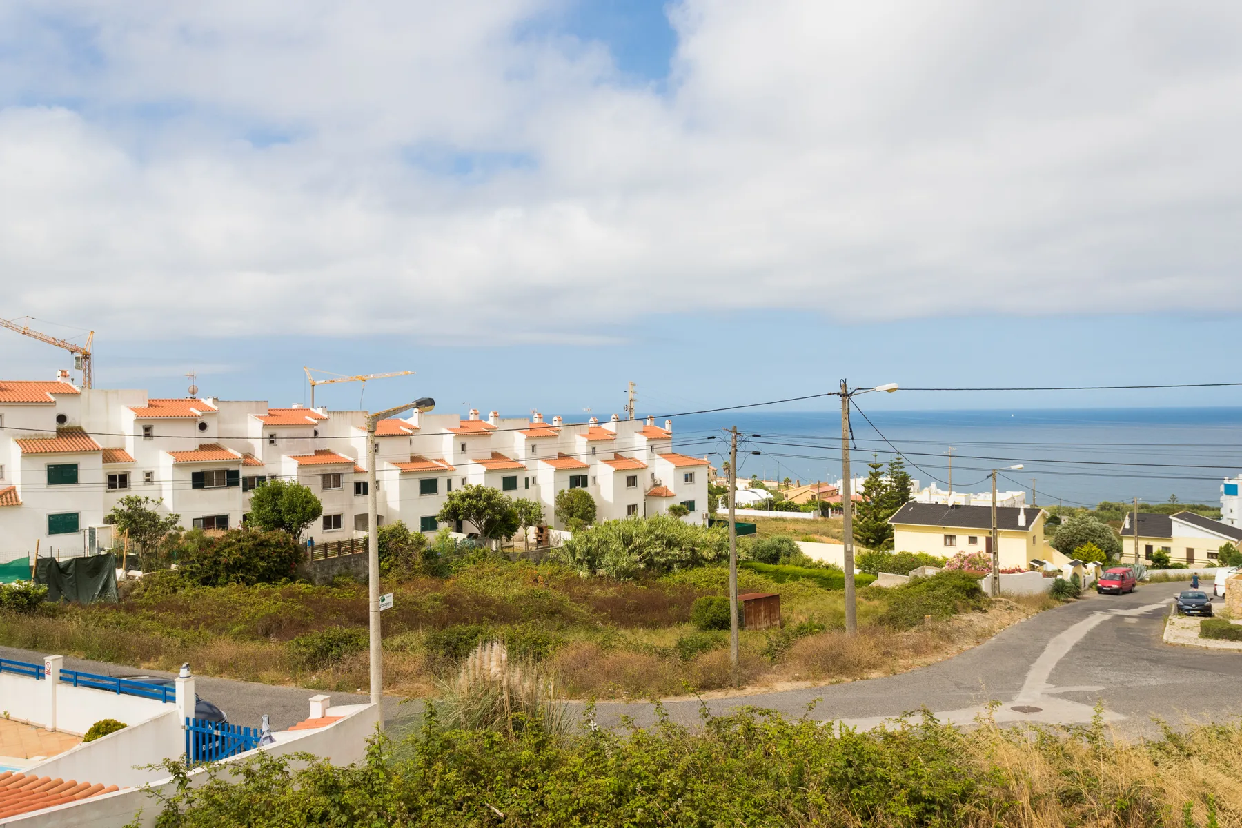 A coastal neighborhood with apartment buildings, a road, and the ocean in the distance.