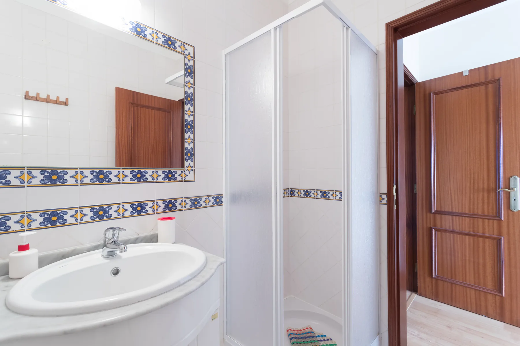 A tiled bathroom with a sink, wall mirror, and shower.