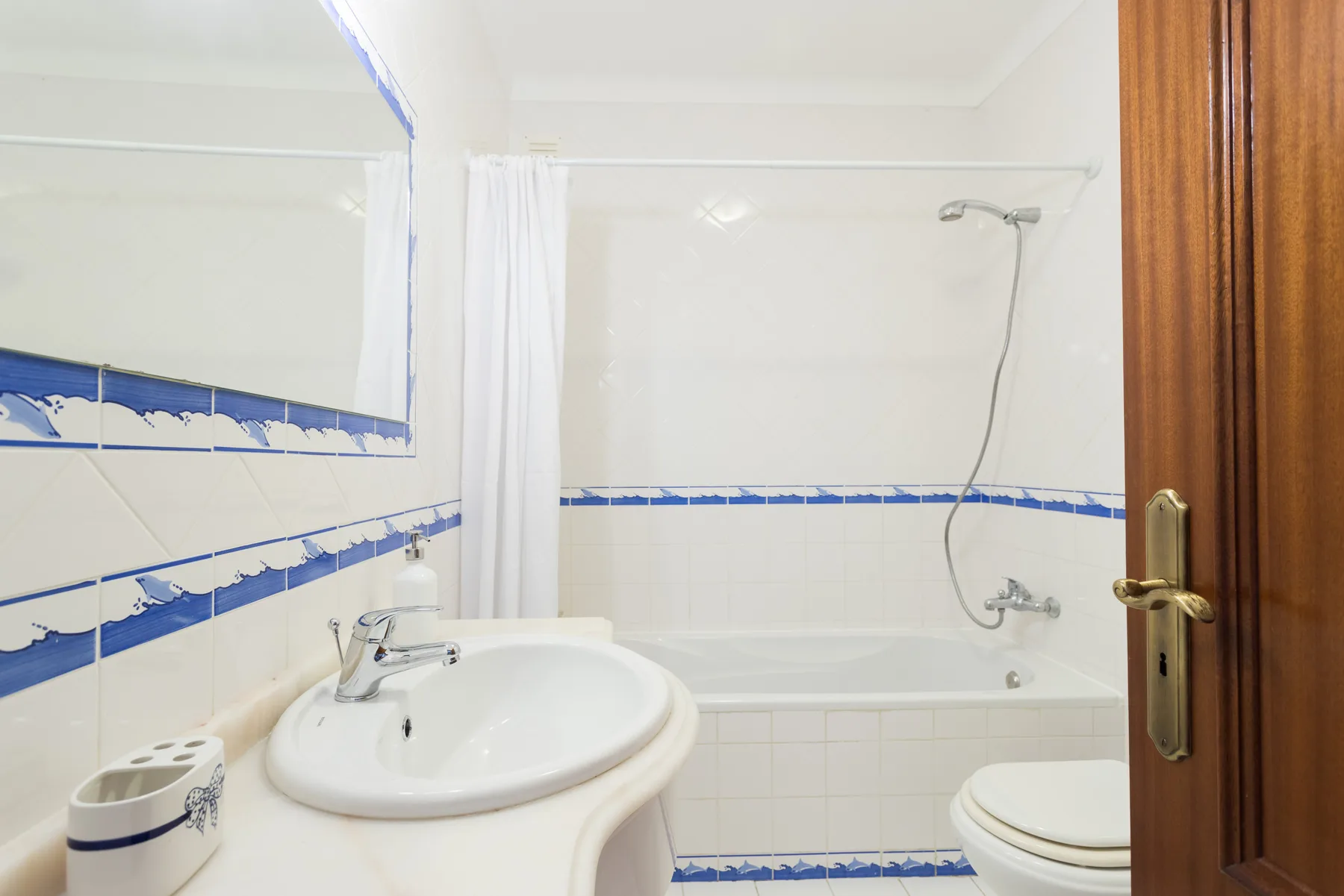 A bathroom with a sink, bathtub, and shower curtain.