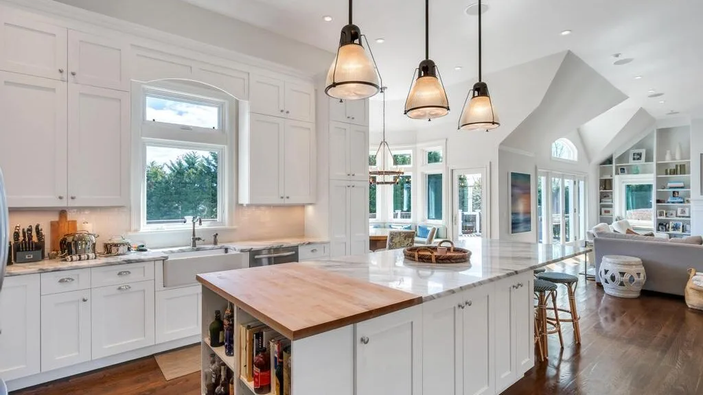 A bright kitchen with white cabinets, a central island, and pendant lights.