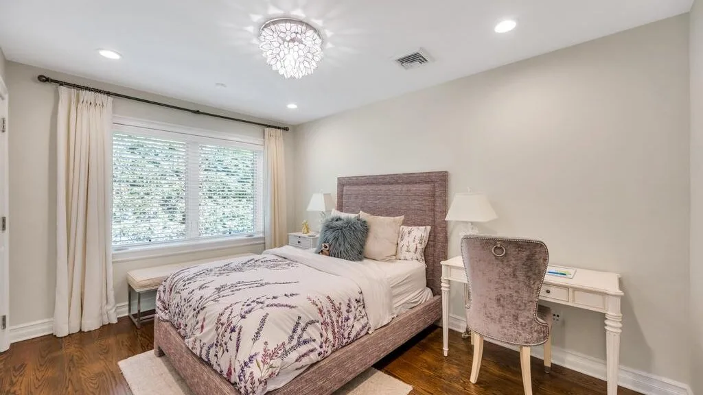 A bedroom with a bed, window, and desk.