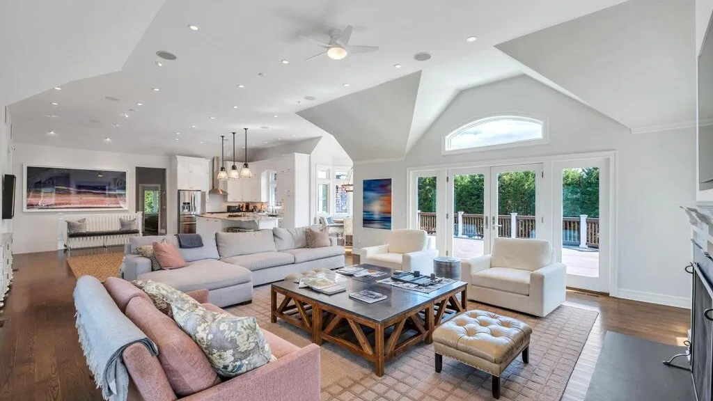 A bright living room with seating arranged around a coffee table and large windows.
