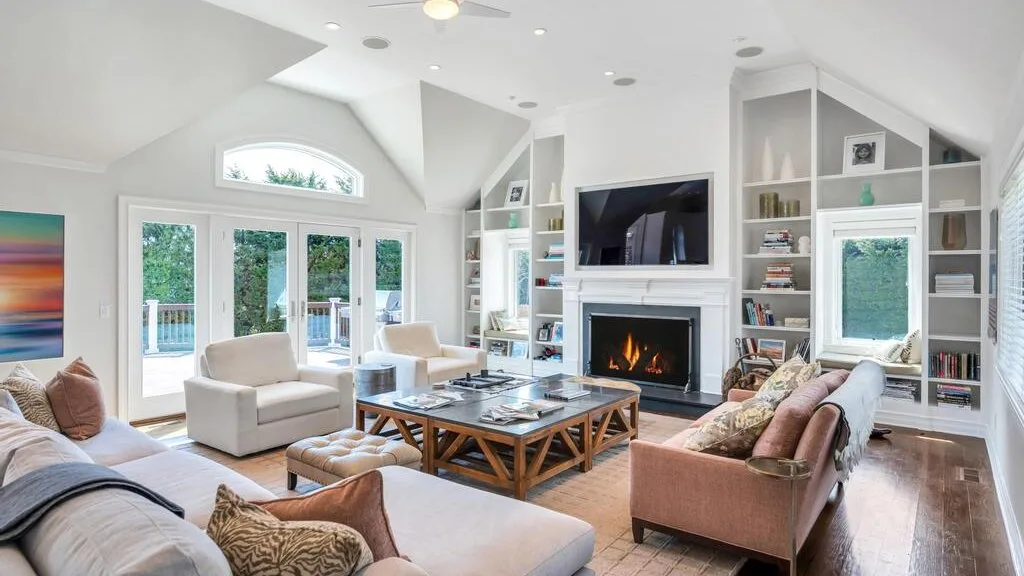 A bright living room with seating arranged around a coffee table and fireplace.