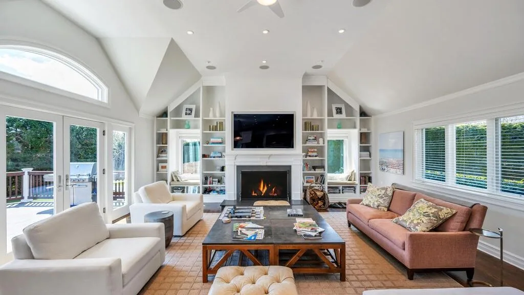 A bright living room features seating around a coffee table and fireplace.