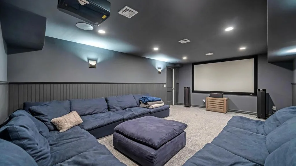A home theater room with a large projection screen and rows of seating.