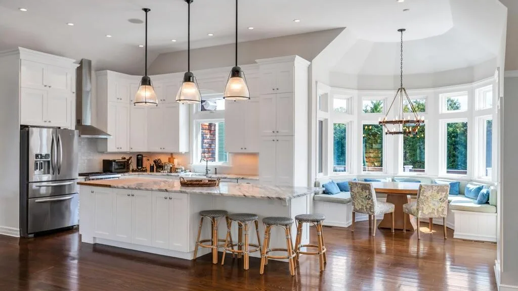 A bright kitchen opens into a dining area with a bay window and built-in seating.