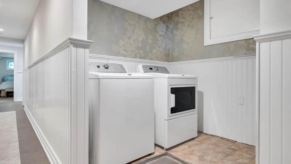 A laundry area with a washer and dryer beside patterned wallpaper.