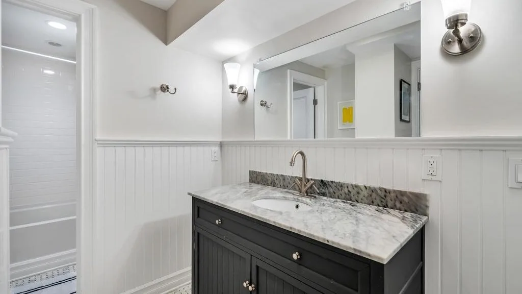 A bathroom vanity with a sink sits beneath a large wall mirror.