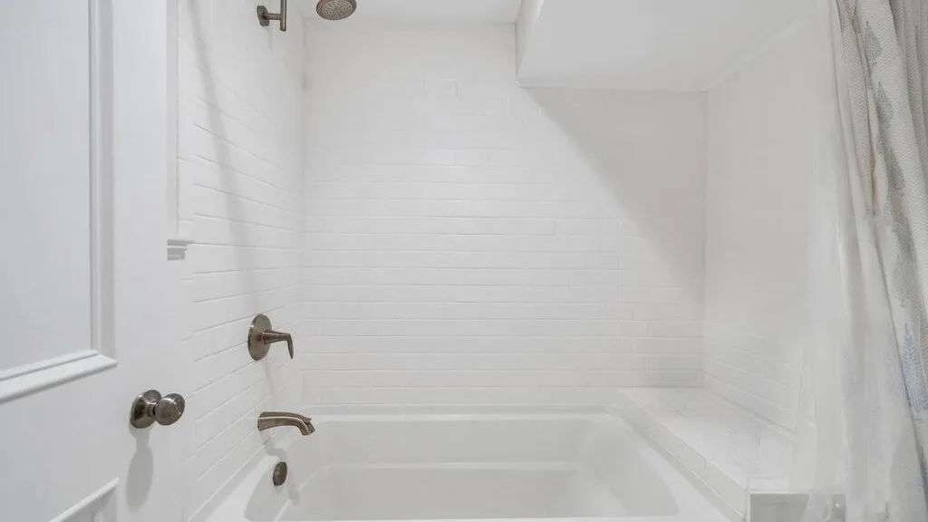 A white bathroom with a bathtub and shower fixtures.