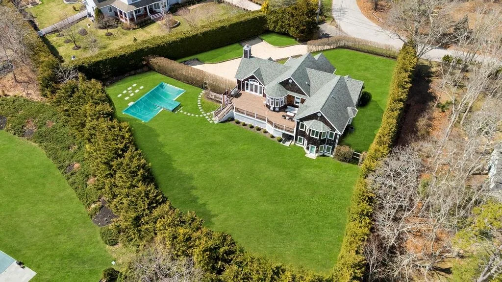 An aerial view shows a large house beside a lawn and swimming pool.