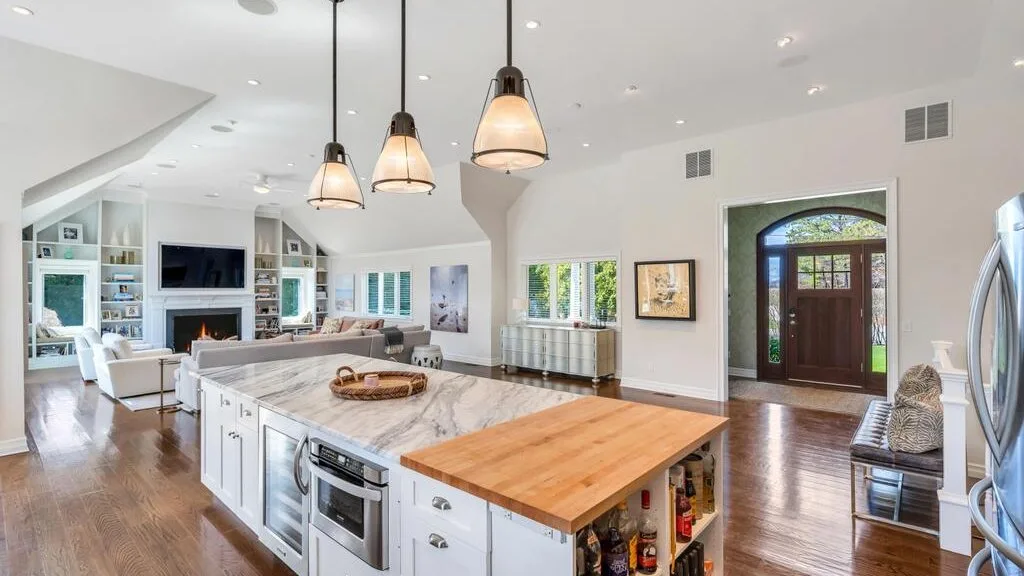 A bright open-plan kitchen and living area with a large island and pendant lights.