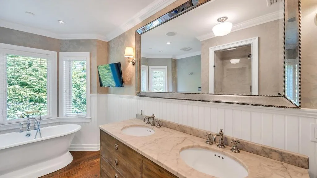 A bathroom with a freestanding bathtub, vanity, and large wall mirror.