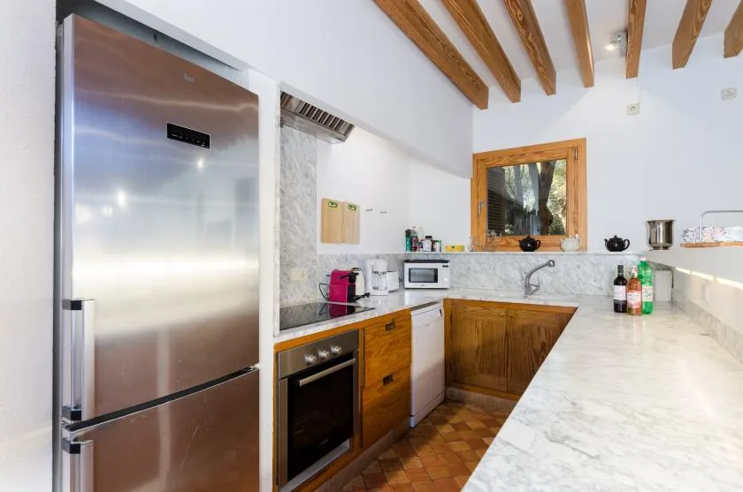 Una cocina luminosa con gabinetes de madera, electrodomésticos de acero inoxidable y vigas expuestas.