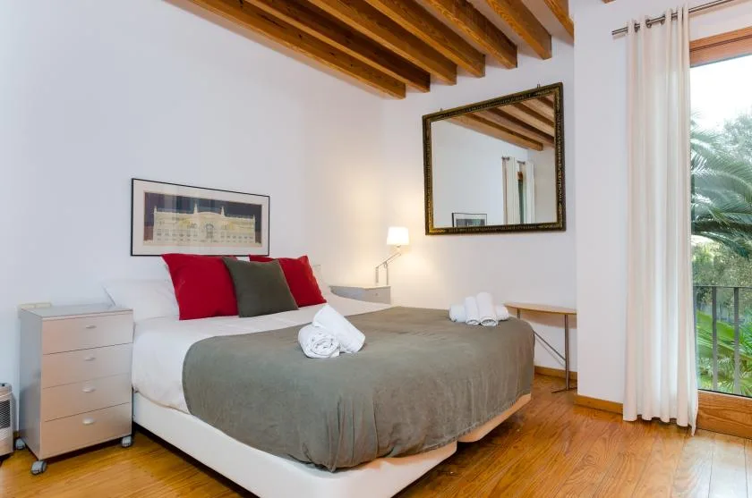 Un dormitorio con una cama, mesitas de noche y una puerta de cristal que da a un balcón.