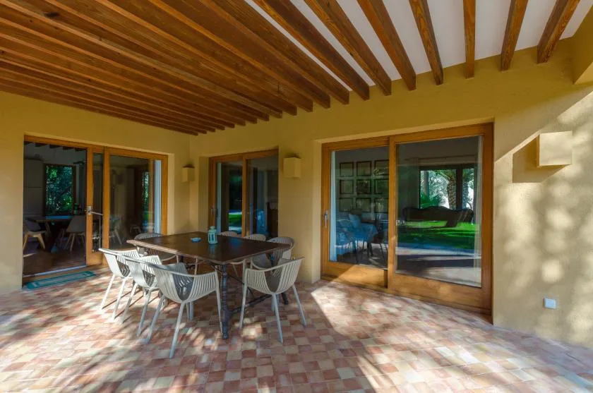 Un comedor exterior cubierto con una mesa y sillas junto a puertas de vidrio.