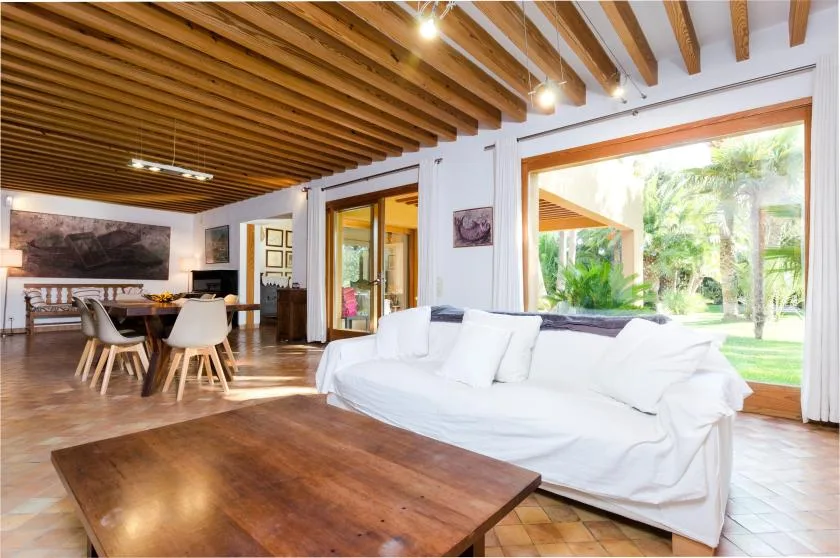 Una sala luminosa con asientos blancos y grandes ventanas que dan a la vegetación.
