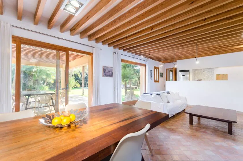 Una luminosa sala de estar y comedor con una larga mesa de madera y ventanas grandes.